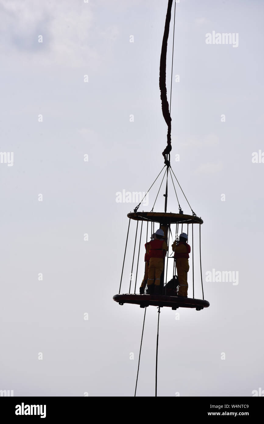 offshore worker inside safety basket hanging in the air Stock Photo