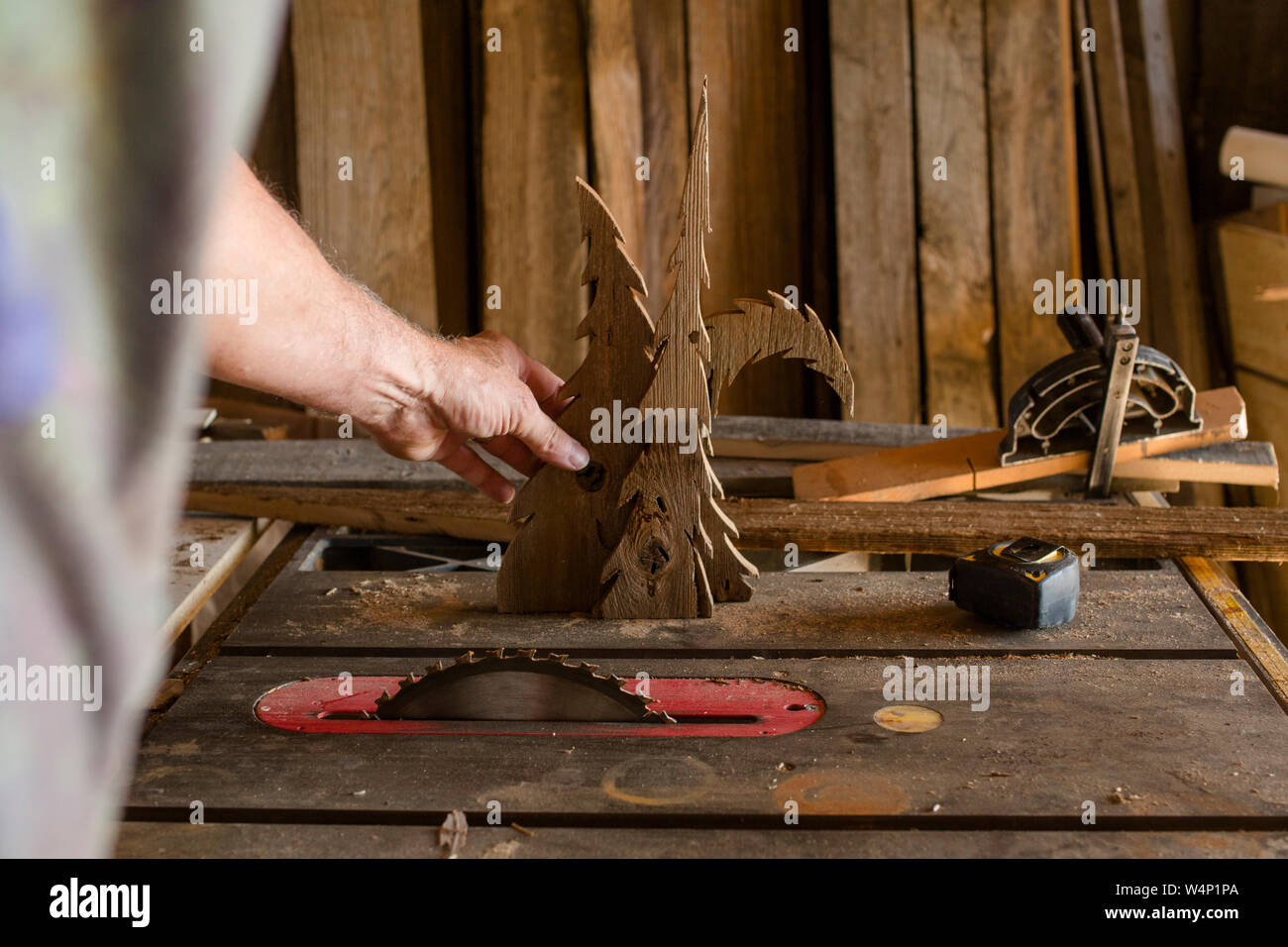 Close-up of a man cutting wooden trees with circular saw on workbench Stock Photo
