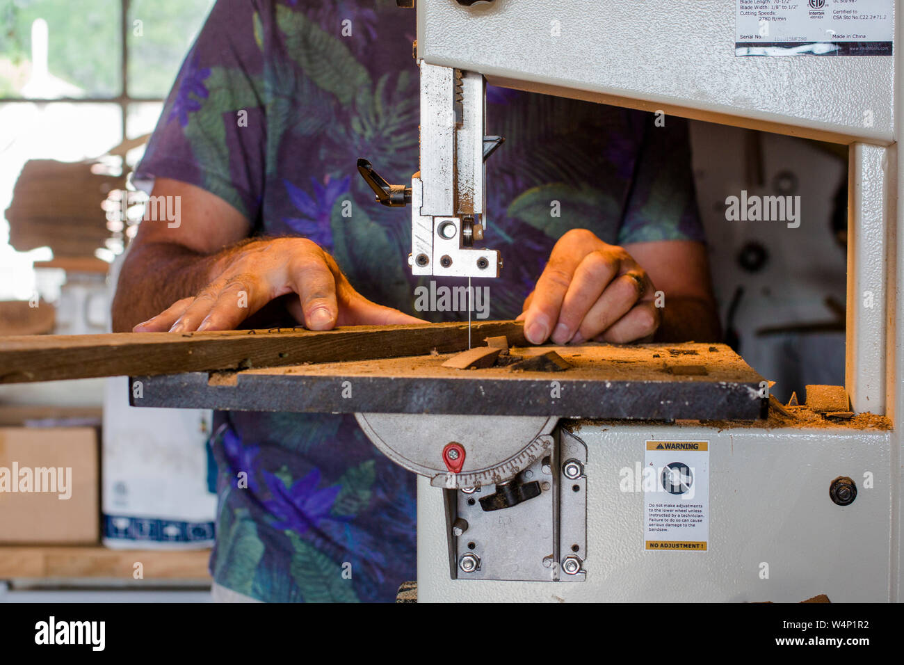 Close-up of man shaping wood on a band saw Stock Photo