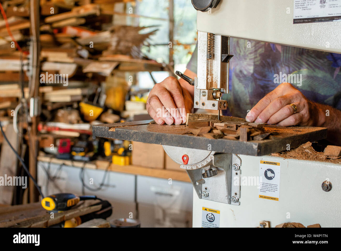 close up view of hands cutting wood on a band saw in workshop Stock Photo