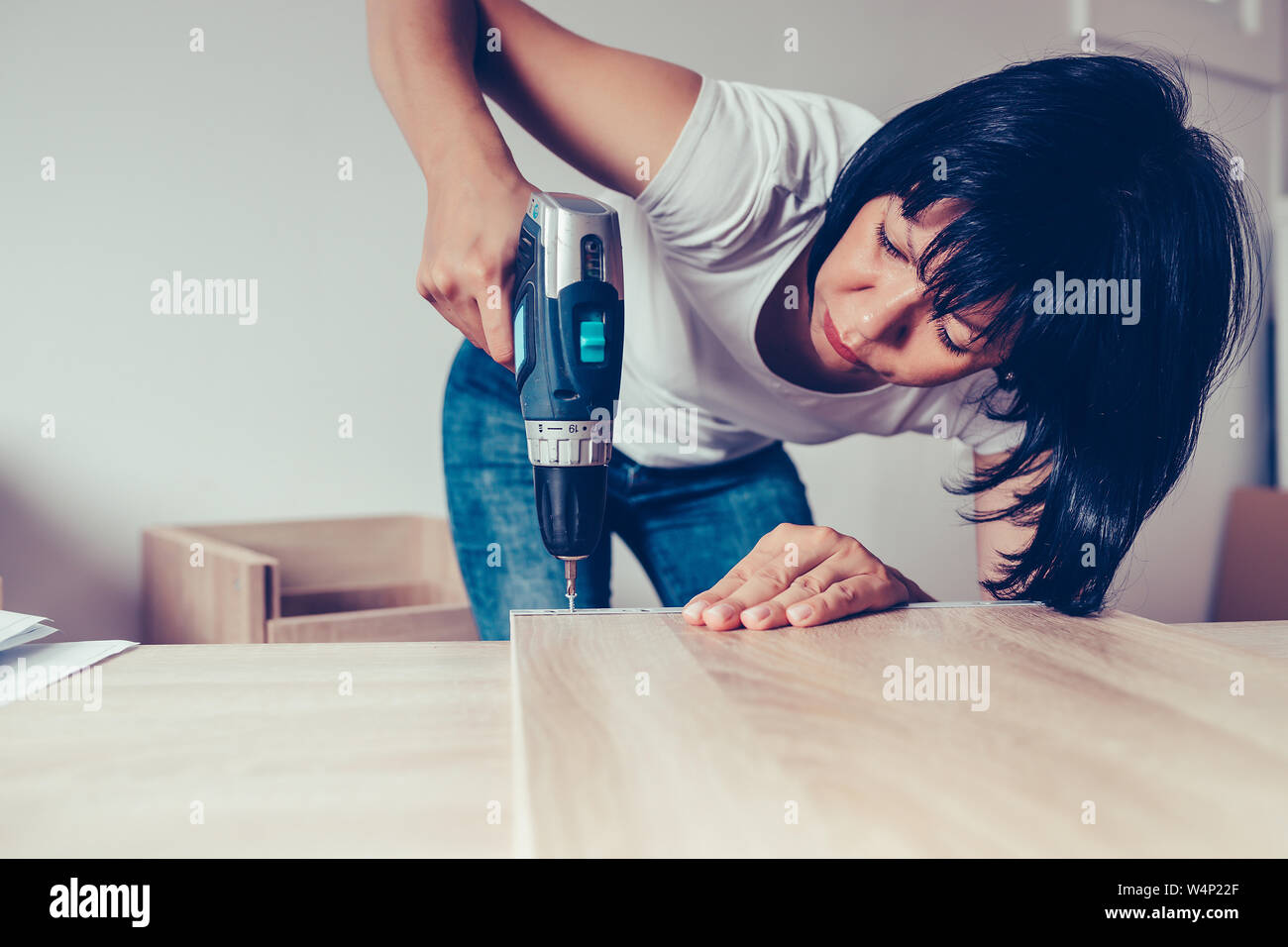 Woman assembling new furniture and using a cordless drill Stock Photo