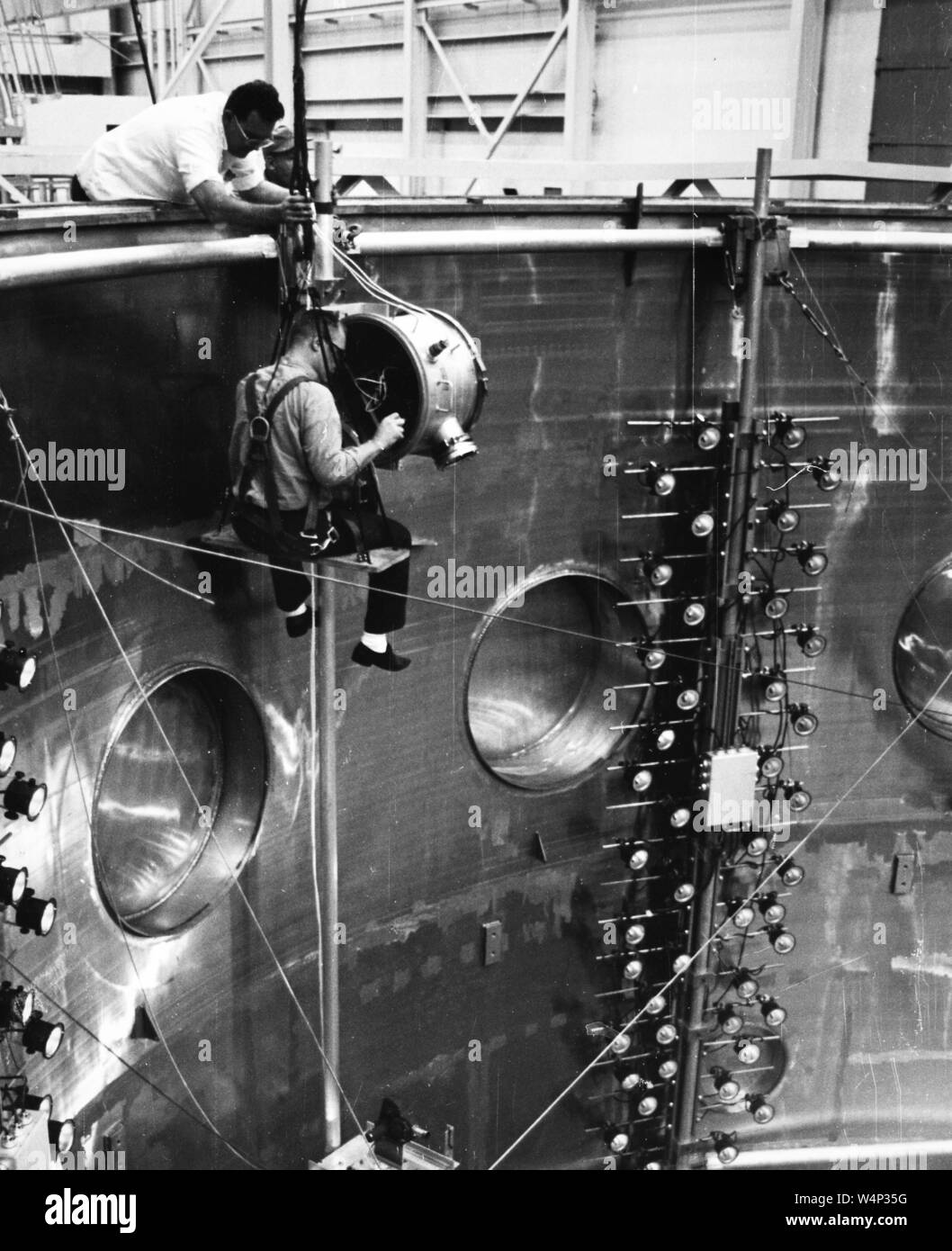 NASA photographers assemble a camera system inside the dynamic test chamber at the Goddard Space Flight Center, Greenbelt, Maryland, 1964. Image courtesy National Aeronautics and Space Administration (NASA). () Stock Photo