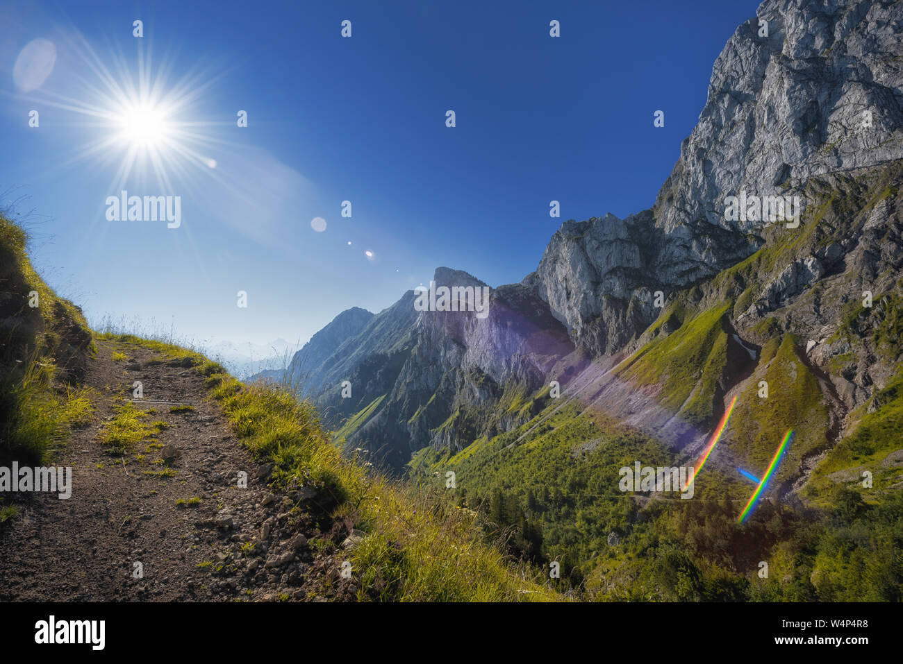 mountain path leading towards the sun, the sunbeams with optical flares Stock Photo