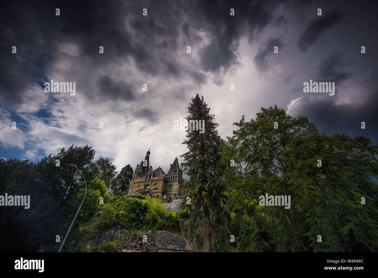 low angle shot of Hünegg castle with dark clouds and spots of blue sky Stock Photo