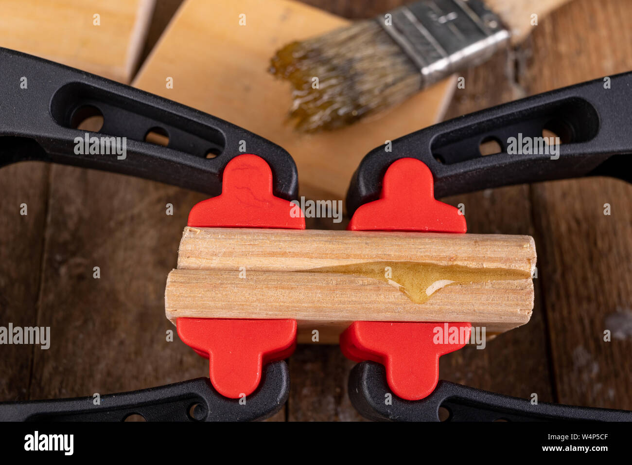 Gluing wood with waterproof adhesive. Pieces of wood pressed together with carpentry clamps. Place - carpentry workshop. Stock Photo