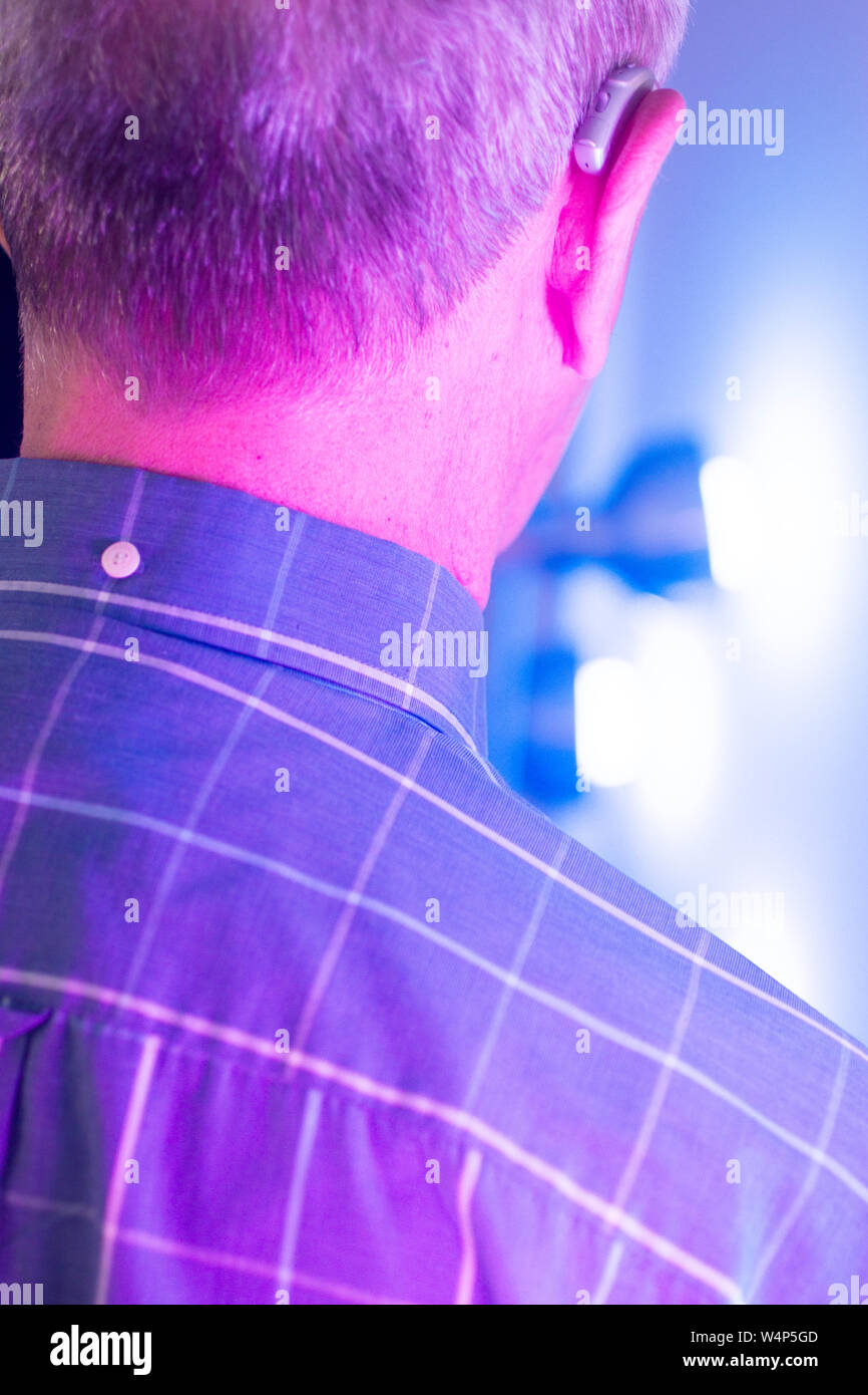 Caucasian white old aged man wearing modern digital hearing aid in ear