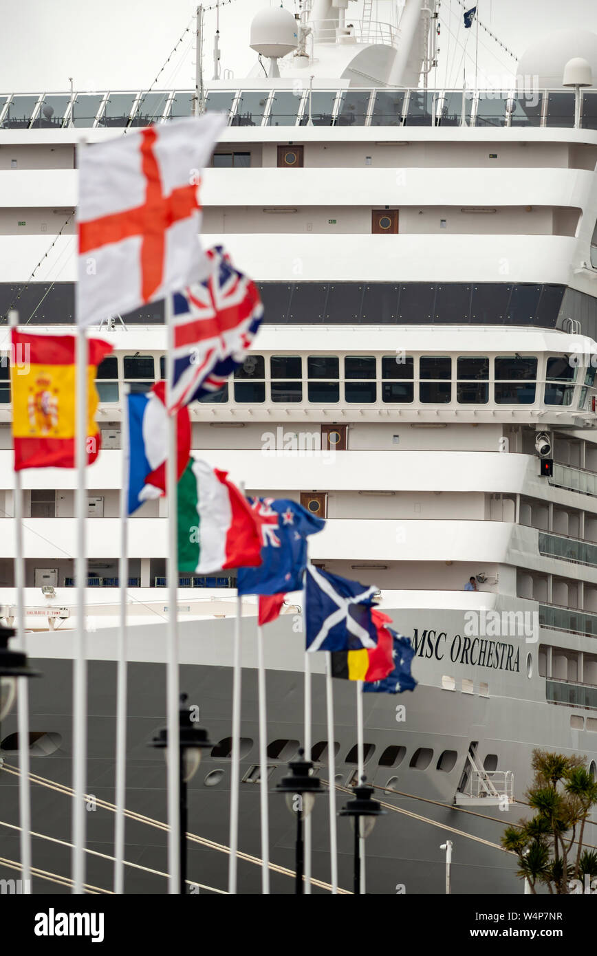 International flags and MSC Orchestra cruise ship passenger liner docking at Cobh cruise terminal. Travel around the world concept, Cobh, Ireland Stock Photo