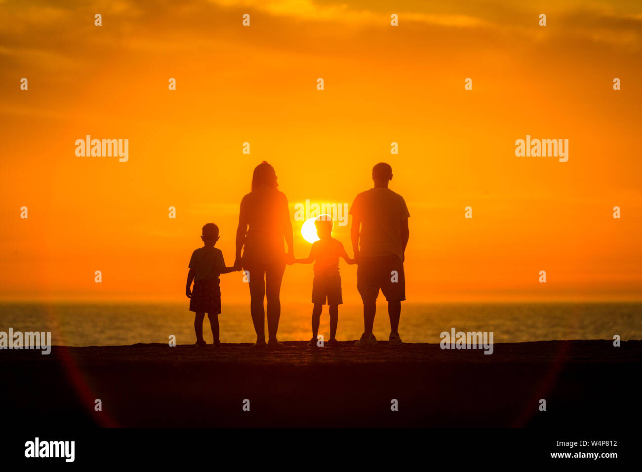 Perfect family watching the sunset over the sea Stock Photo