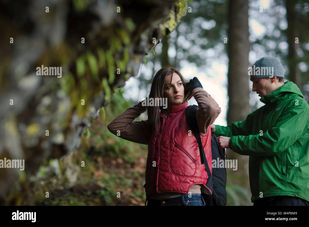 Young man looking in backpack of girlfriend while on a hike. Stock Photo