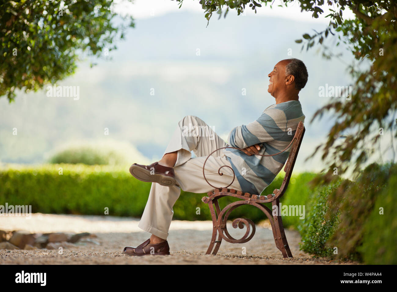 Smiling mature man sitting on a park bench Stock Photo - Alamy