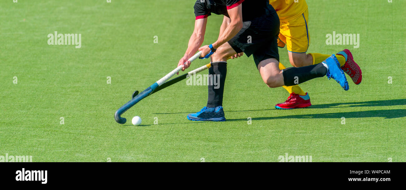 Two field hockey player, fighting for the ball on the midfield during