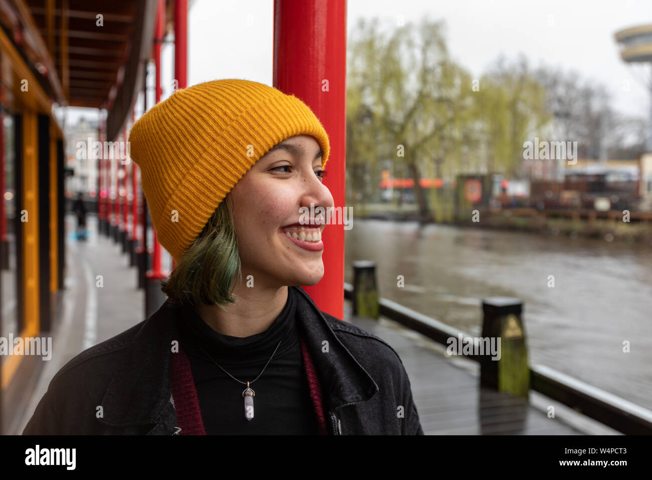 Head and shoulders of smiling young woman looking on water canal. Stock Photo