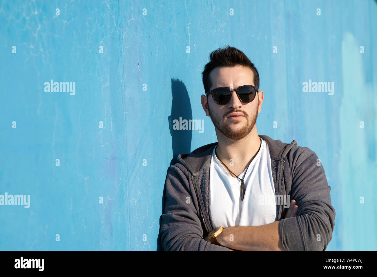 Portrait of young bearded man with sunglasses leaning against wall Stock Photo