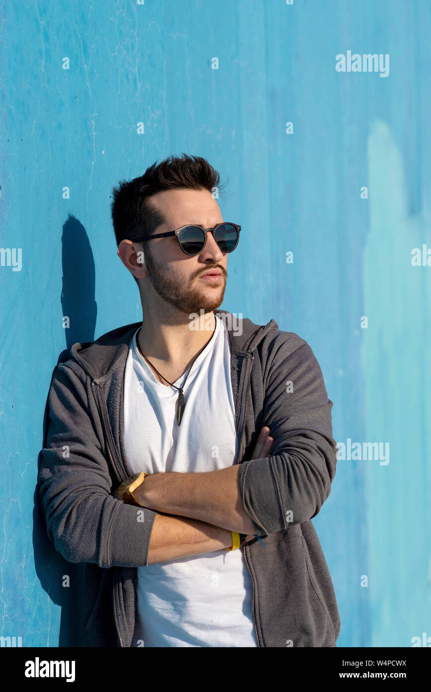 Portrait of young bearded man with sunglasses leaning against wall Stock Photo