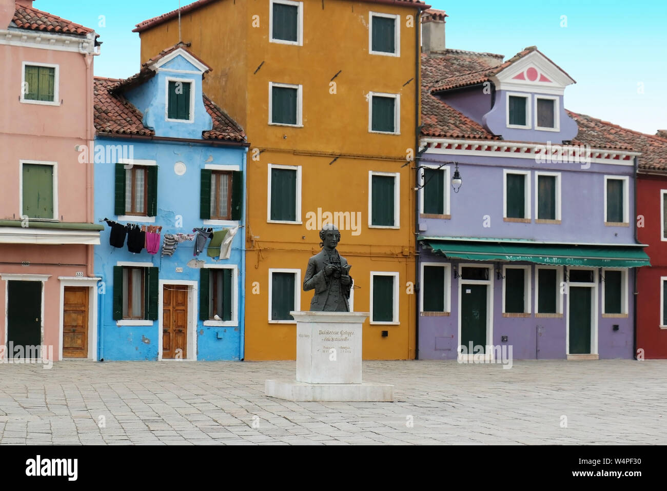 Burano, Italy - January 10, 2017; The statue of Venetian composer Baldassare Galuppi in the main square of Burano island with famous retro houses Stock Photo