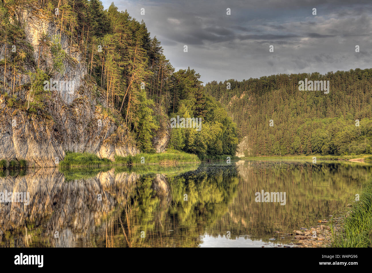 Rocks and forest are reflected in the river, cloudy summer day, South ...