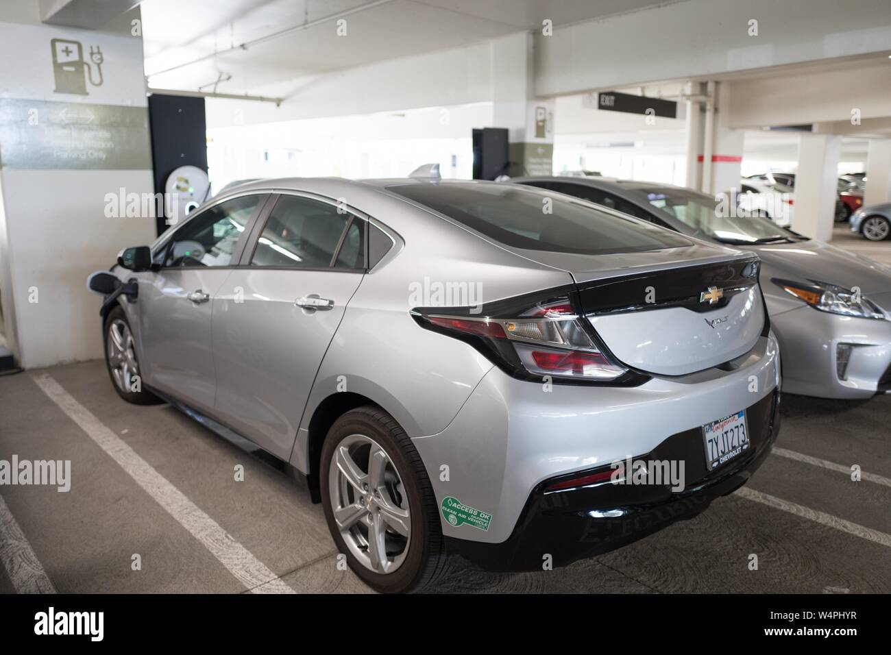 Chevrolet Volt electric vehicle plugged in and charging at an electric vehicle charging station in San Ramon, California, with California Access Okay clean air vehicle sticker visible, September 26, 2018. () Stock Photo