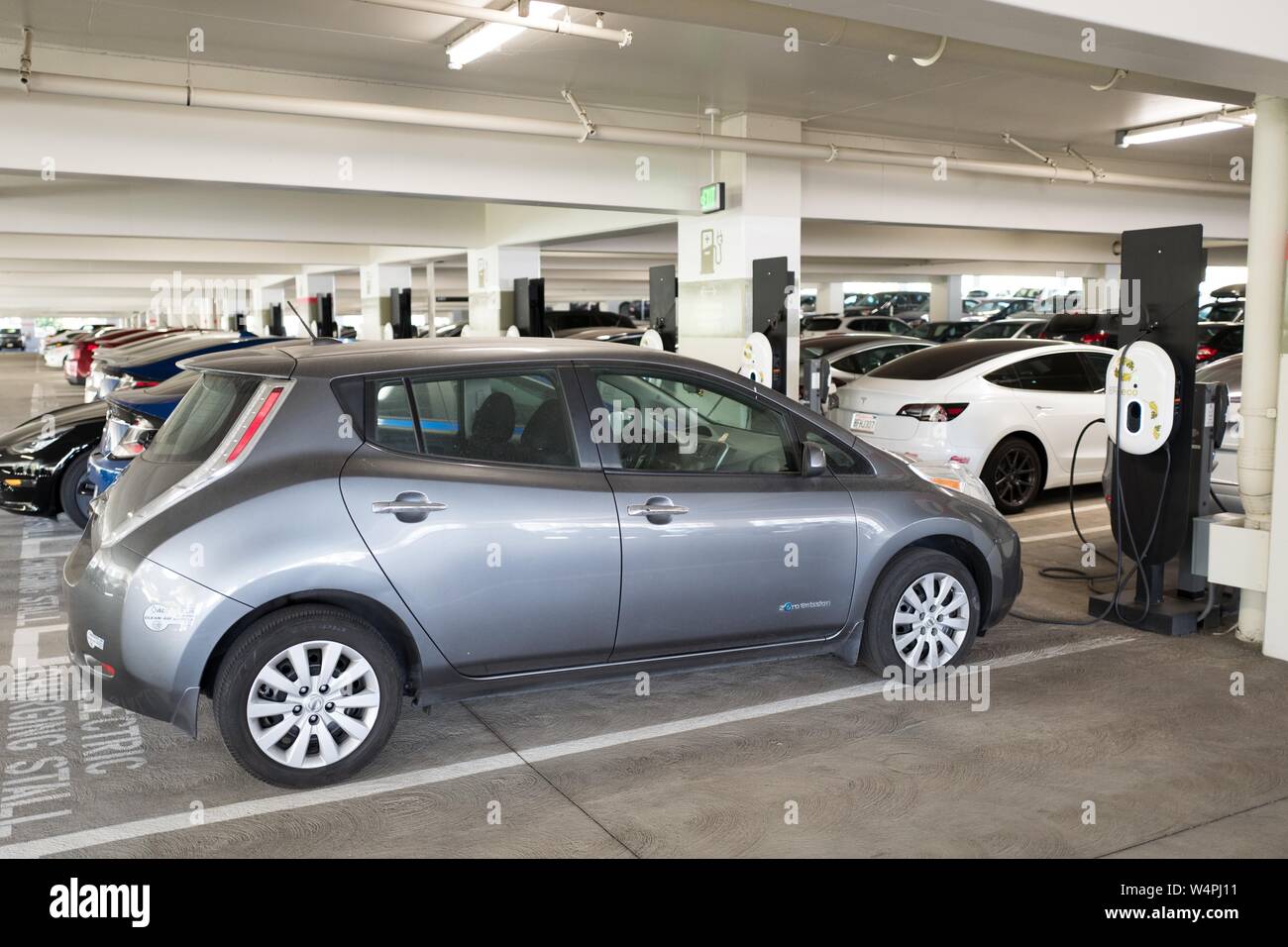 Nissan Leaf electric car plugged in and charging at an electric vehicle