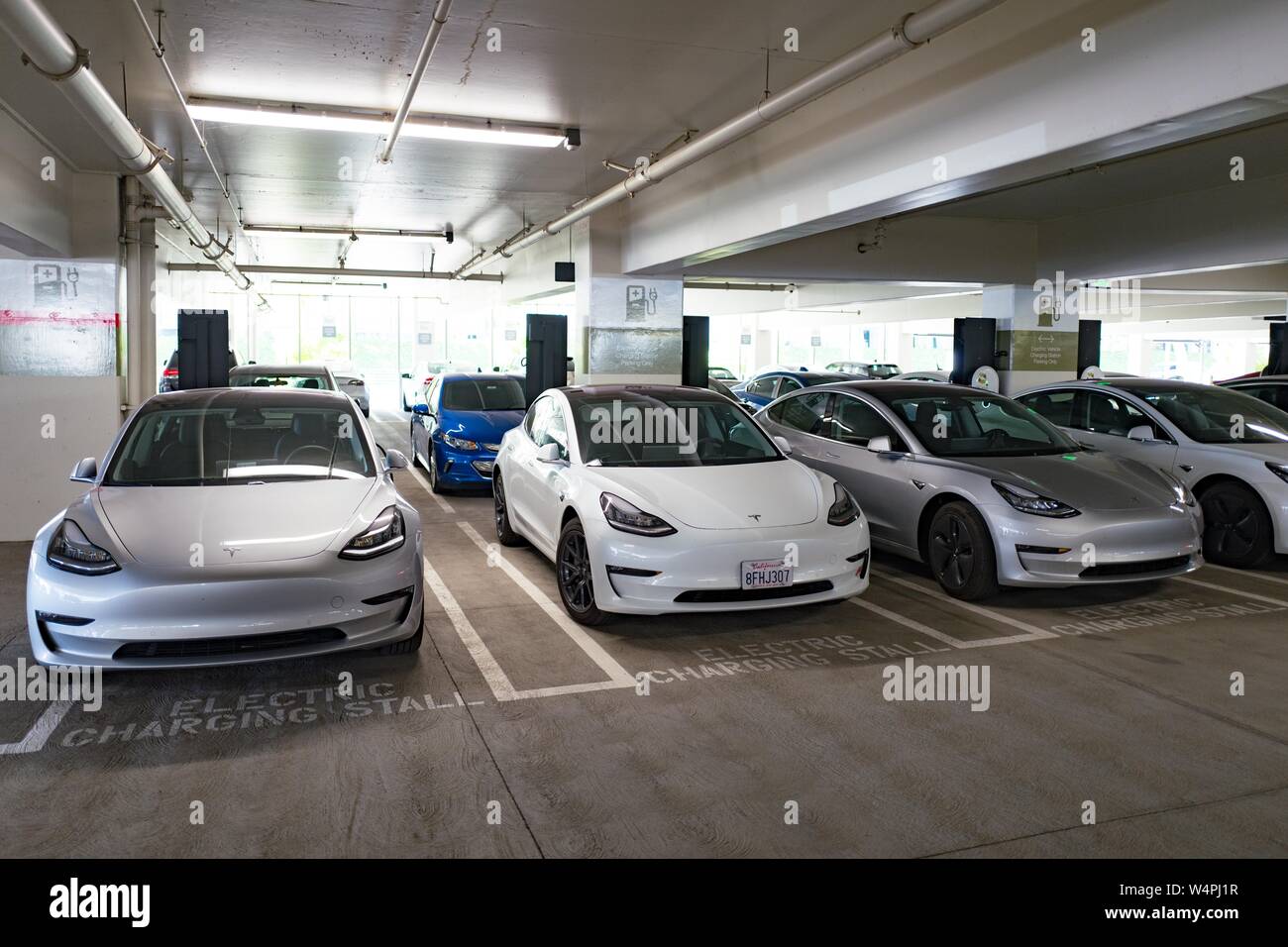 Four Tesla Model 3 electric cars from Tesla Motors are visible charging
