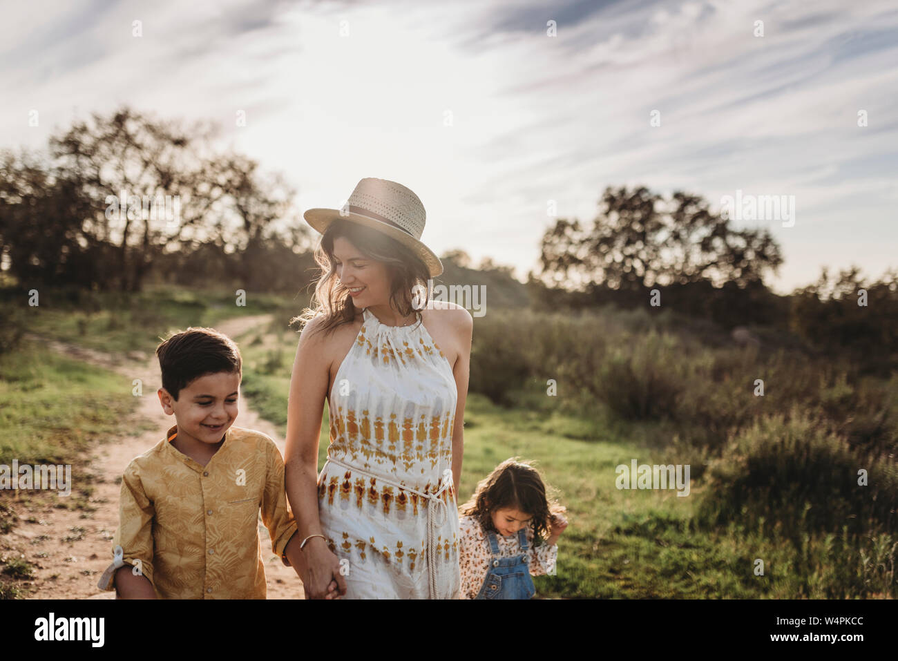 Young mother, son, and daughter holding hands while walking in field Stock Photo