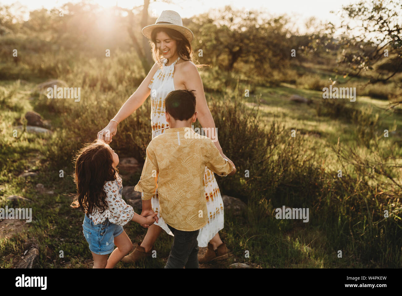 Close up of mother in hat playing ring around the rosie with children Stock Photo