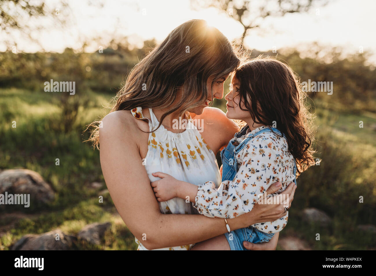 Young mother holding daughter and cuddling in bright california field Stock Photo