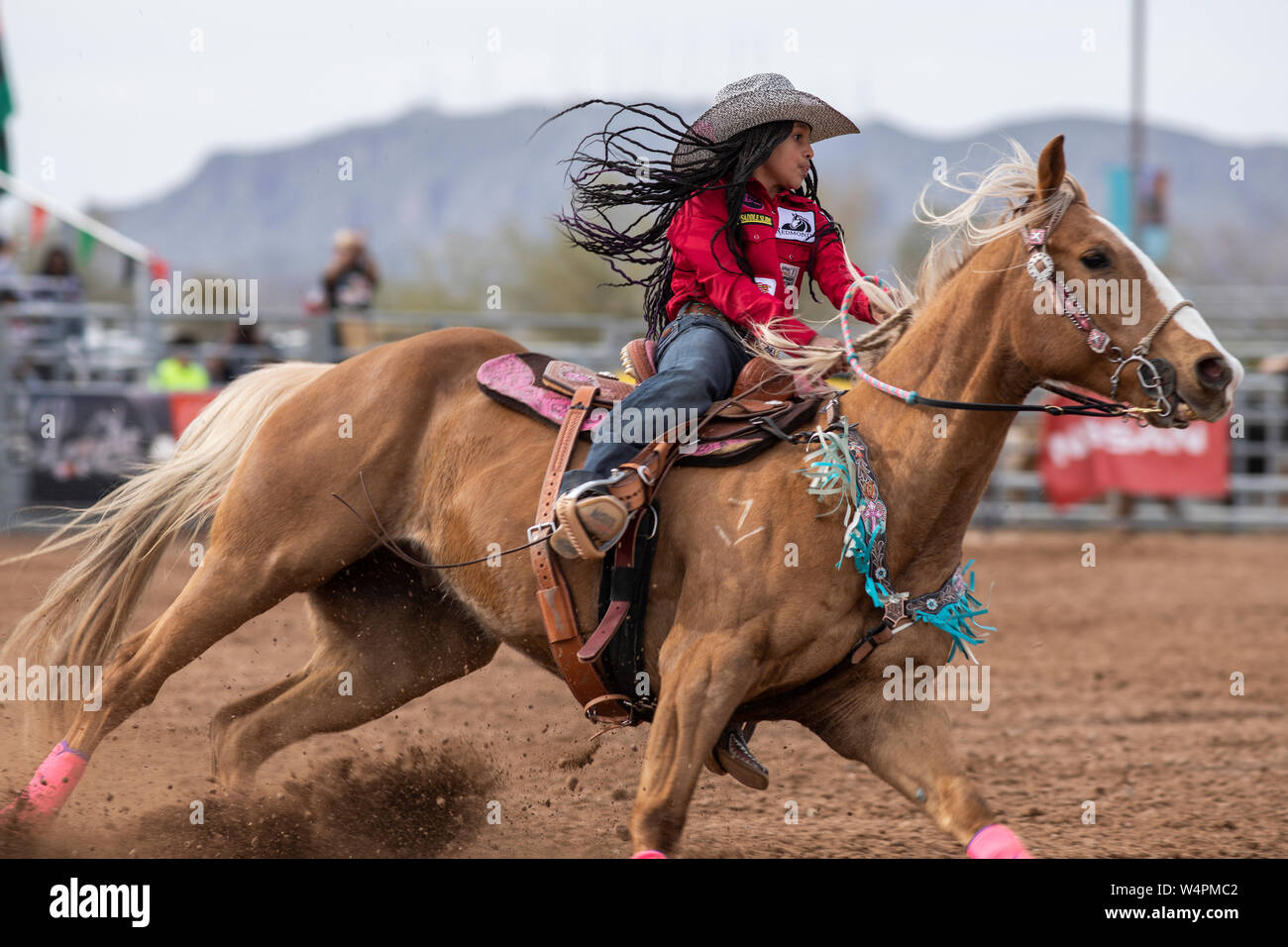 A young woman rides in the barrel racing event at the AZ black rodeo