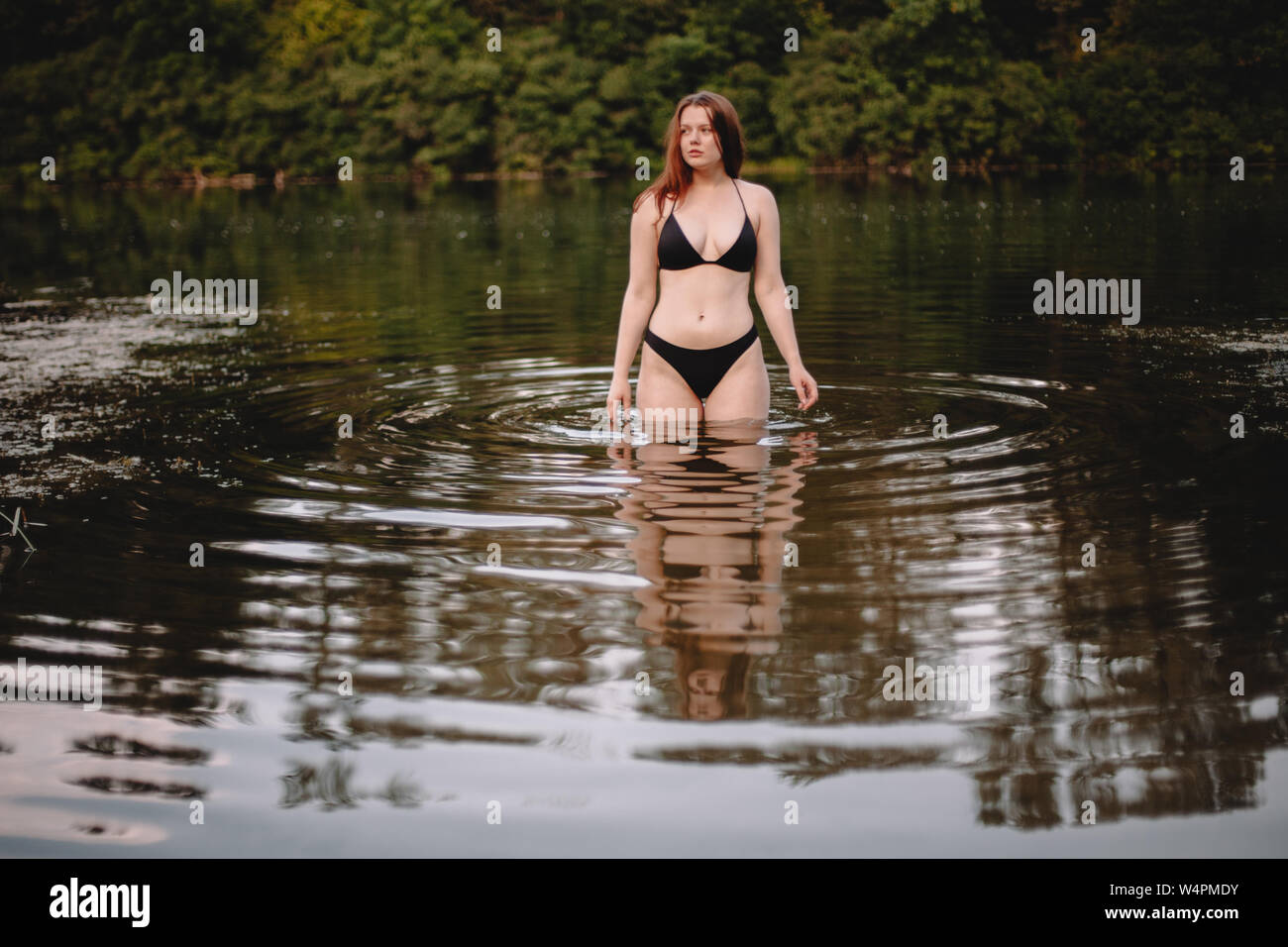 Front view of young woman standing in lake Stock Photo