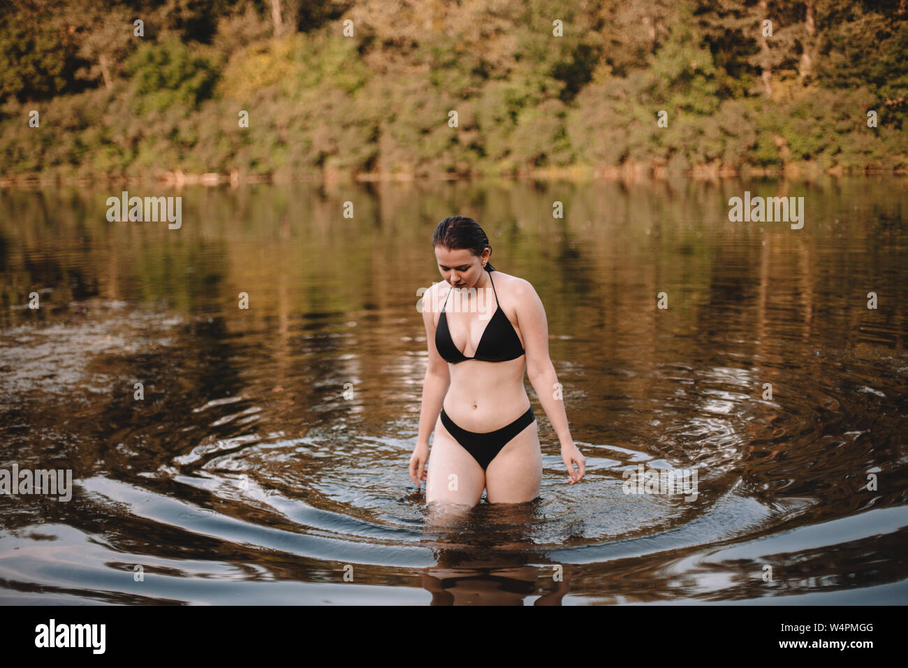 Young woman in a bikini walking in lake Stock Photo