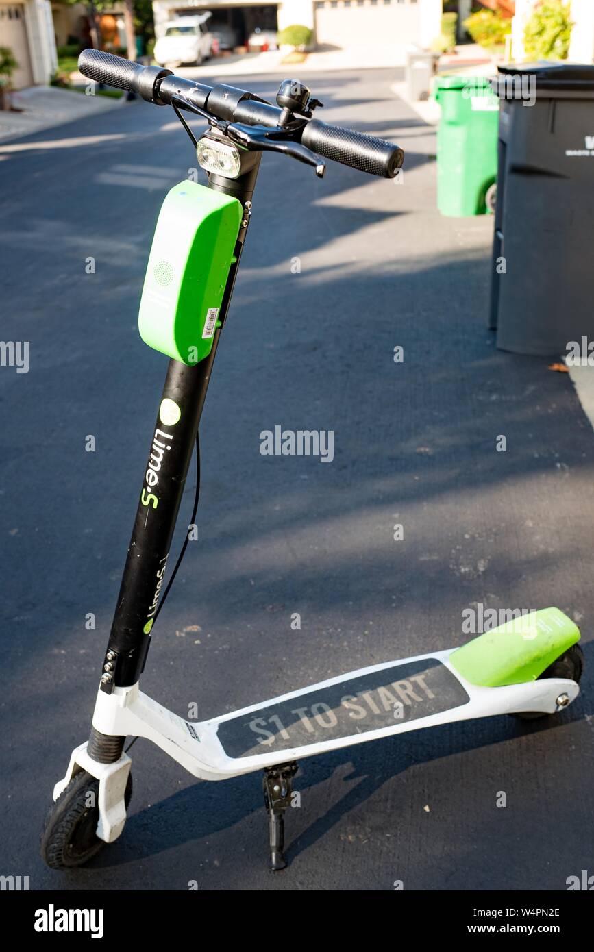 Full-length view of Lime dockless electric scooter in San Ramon, California parked on an asphalt road surface in a suburban setting, October 18, 2018. () Stock Photo