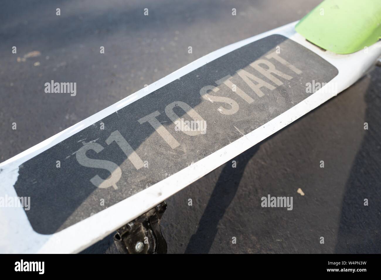 Close-up of running board on a Lime dockless electric scooter in San Ramon, California parked on an asphalt road surface, with text reading $1 to start, describing the pricing model for riders of the scooter, October 18, 2018. () Stock Photo