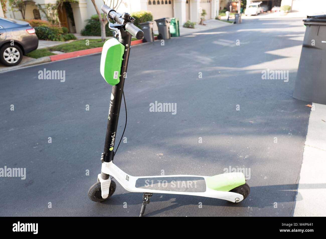 Full length view of Lime dockless electric scooter in San Ramon, California parked on an asphalt road surface, October 18, 2018. () Stock Photo