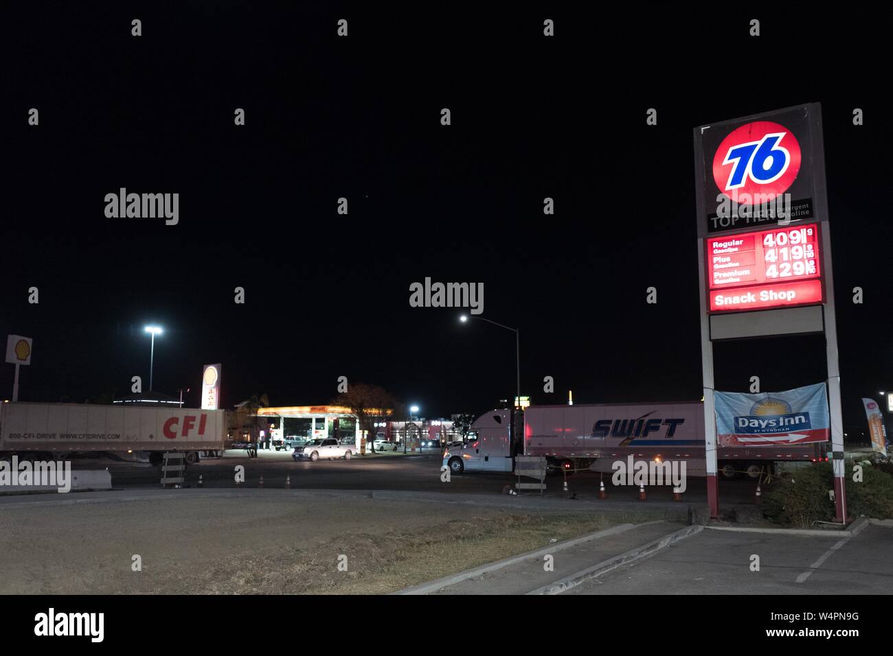 Signs for gas stations, including a Philips 76 station, are visible with semi trucks driving past at a truck stop along the 5 Freeway late at night in Lost Hills, California, October 19, 2018. () Stock Photo