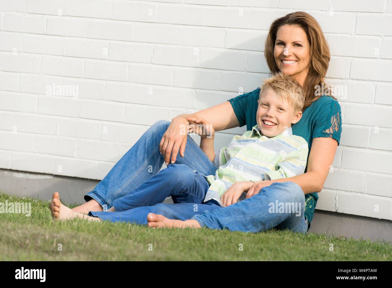 Mother and son sit together in front of a white wall look into the
