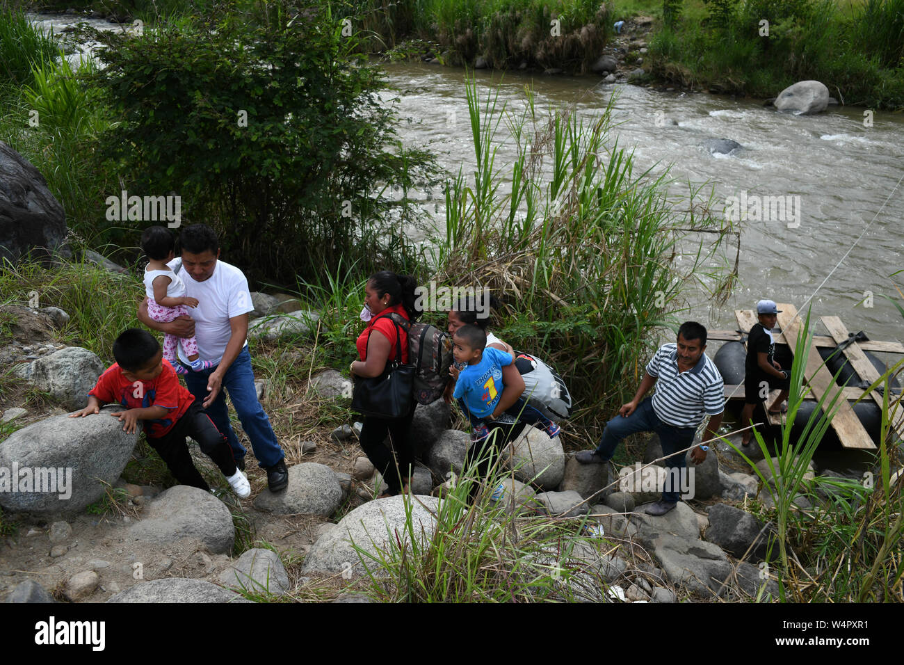July 24, 2019, Talisman, Chiapas, Mexico: Central American families cross illegally into Mexico on a tube boat from El Carmen town into Talisman Wednesday. The migrants pay 50 cents per person, and dozen cross illegally every day, even as the administration of Mexican President Lopez Obrador claims to have reduced the flow of migrants heading to the US by more than 36% last month. Frustrated Mexican marines and immigration officers say that they have been reduced to observers, since they lack the judiciary tools to address the issue and even weapons to defend themselves against smugglers and Stock Photo