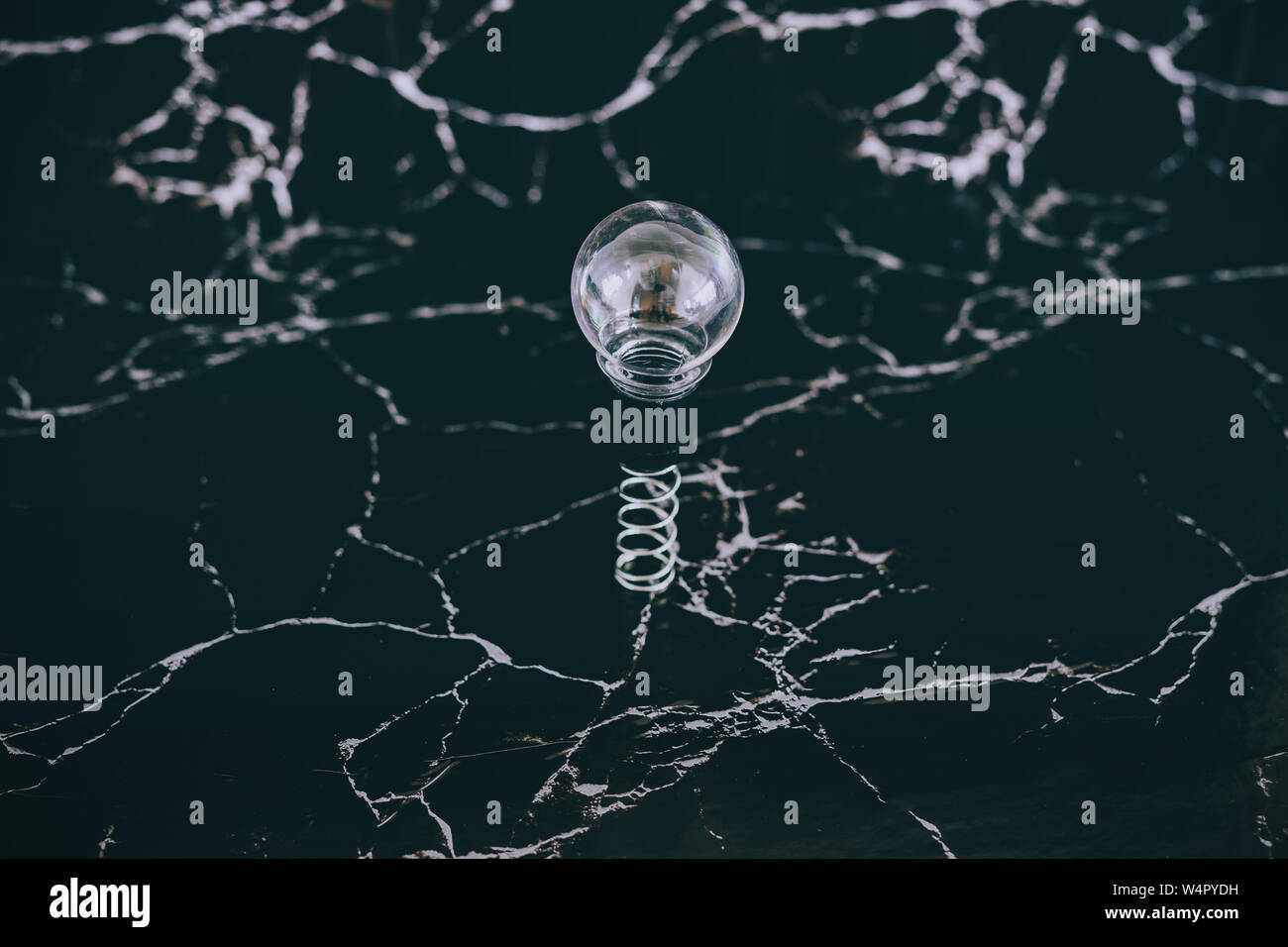 idea lightbulb popping up on spring with black marble background