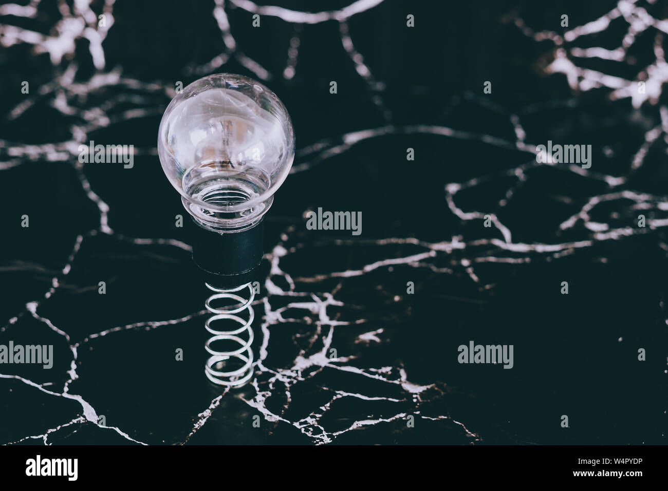 idea lightbulb popping up on spring with black marble background