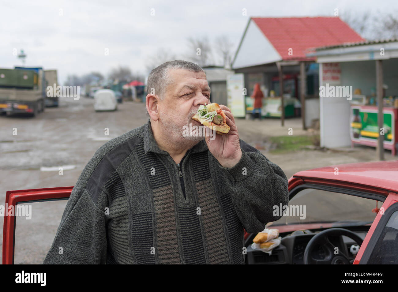 Senior driver gobbling lyulya kebab in lavash near his car Stock Photo