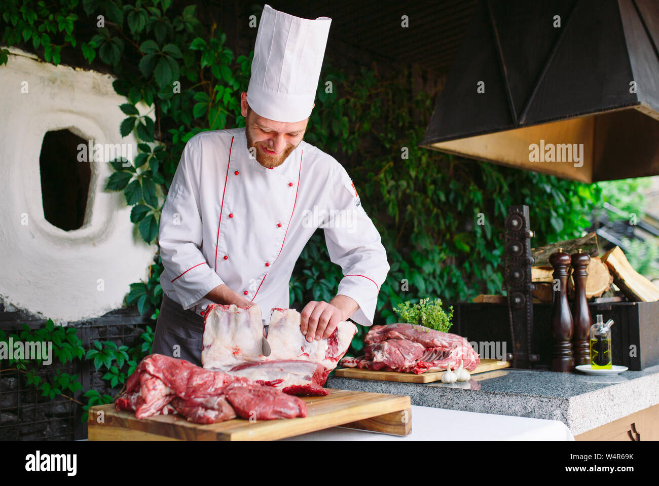 A man cook cuts meat with a knife in a restaurant Stock Photo