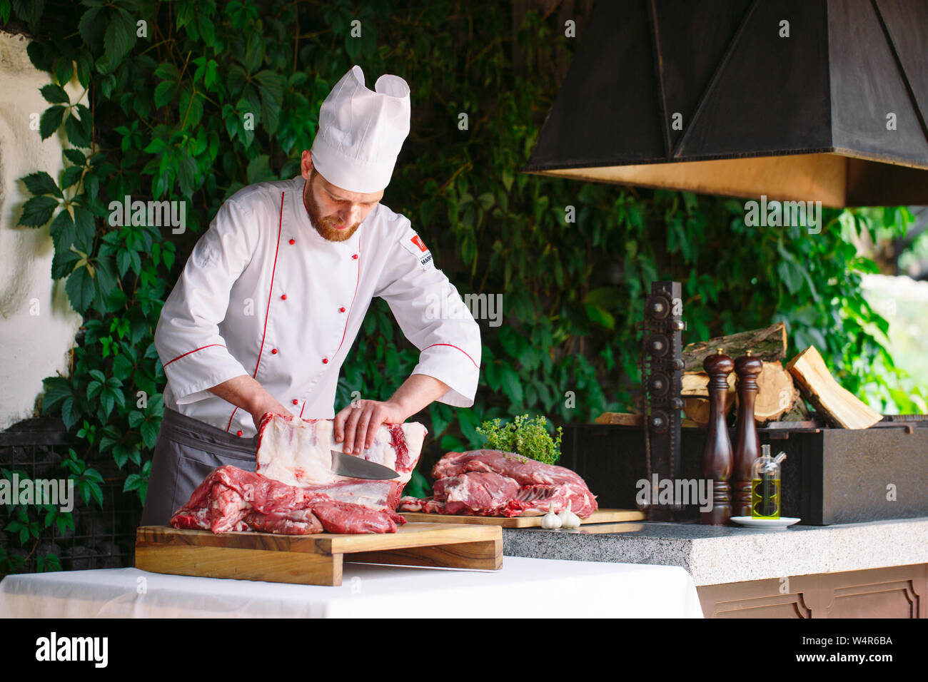A man cook cuts meat with a knife in a restaurant Stock Photo - Alamy