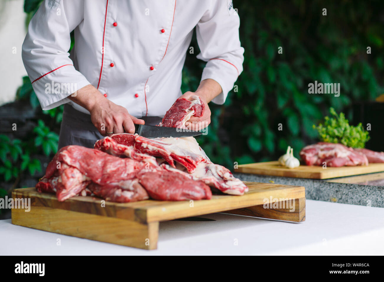 A man cook cuts meat with a knife in a restaurant Stock Photo