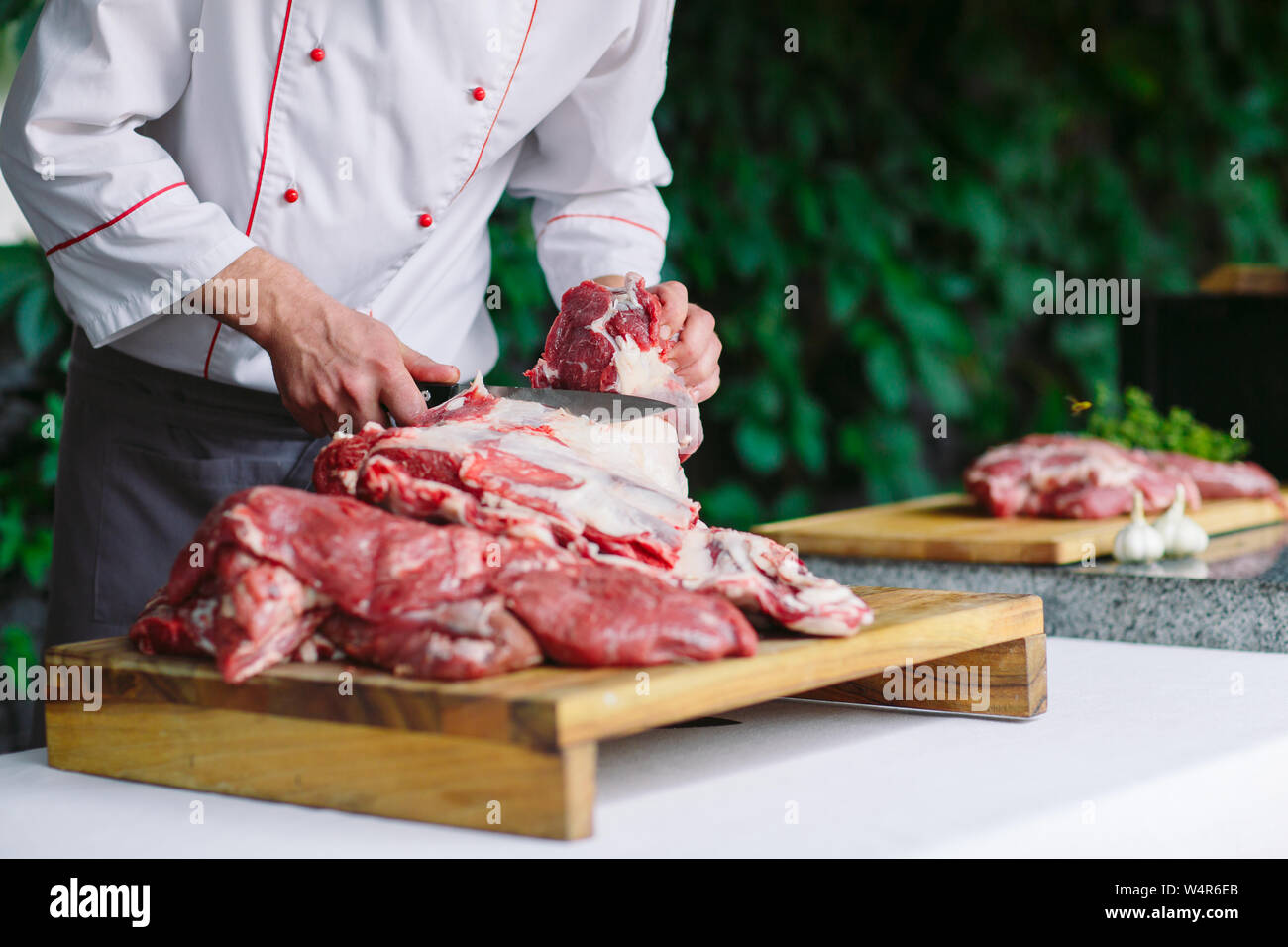 A man cook cuts meat with a knife in a restaurant Stock Photo