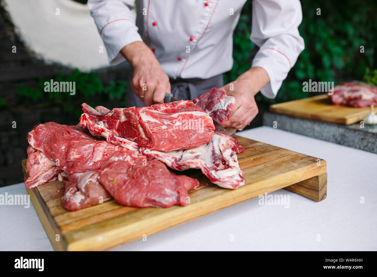 A man cook cuts meat with a knife in a restaurant Stock Photo