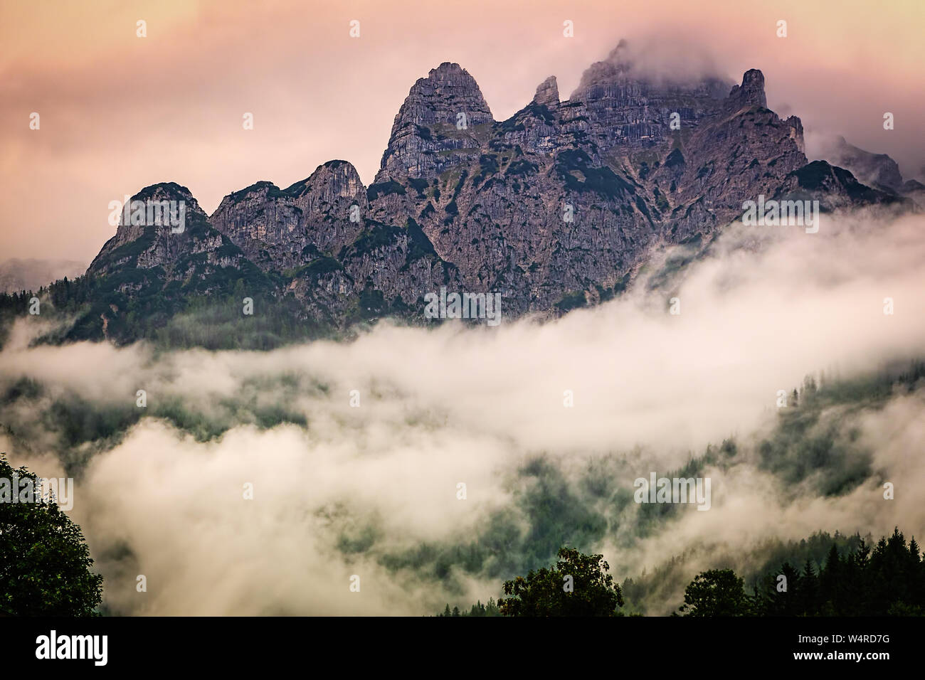 Rocky mountain ridge in Austrian Alps in the evening, dramatic foggy landscape. Stock Photo