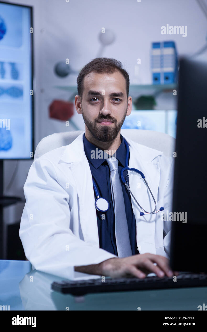 Portrait of attractive caucasian doctor looking into the camera sitting at his office. Handsome doctor. Stock Photo