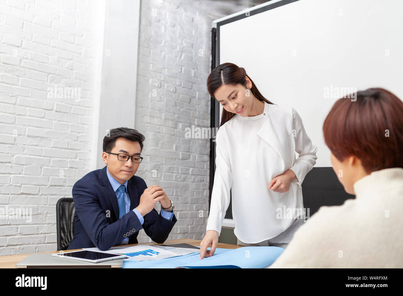 Young architect presenting blueprint in meeting room, Beijing, China Stock Photo