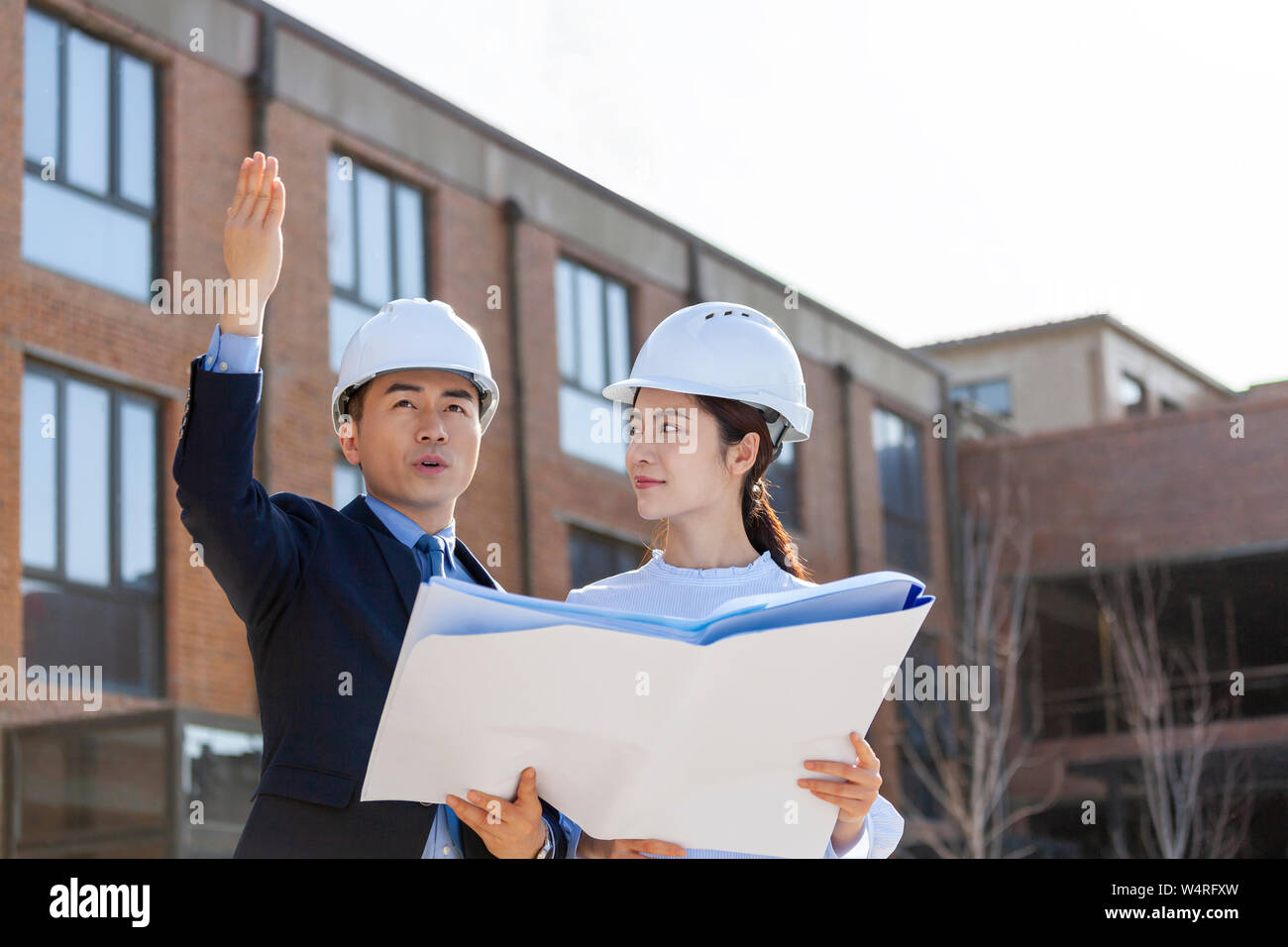 Two architects talking over blueprints, Beijing, China Stock Photo