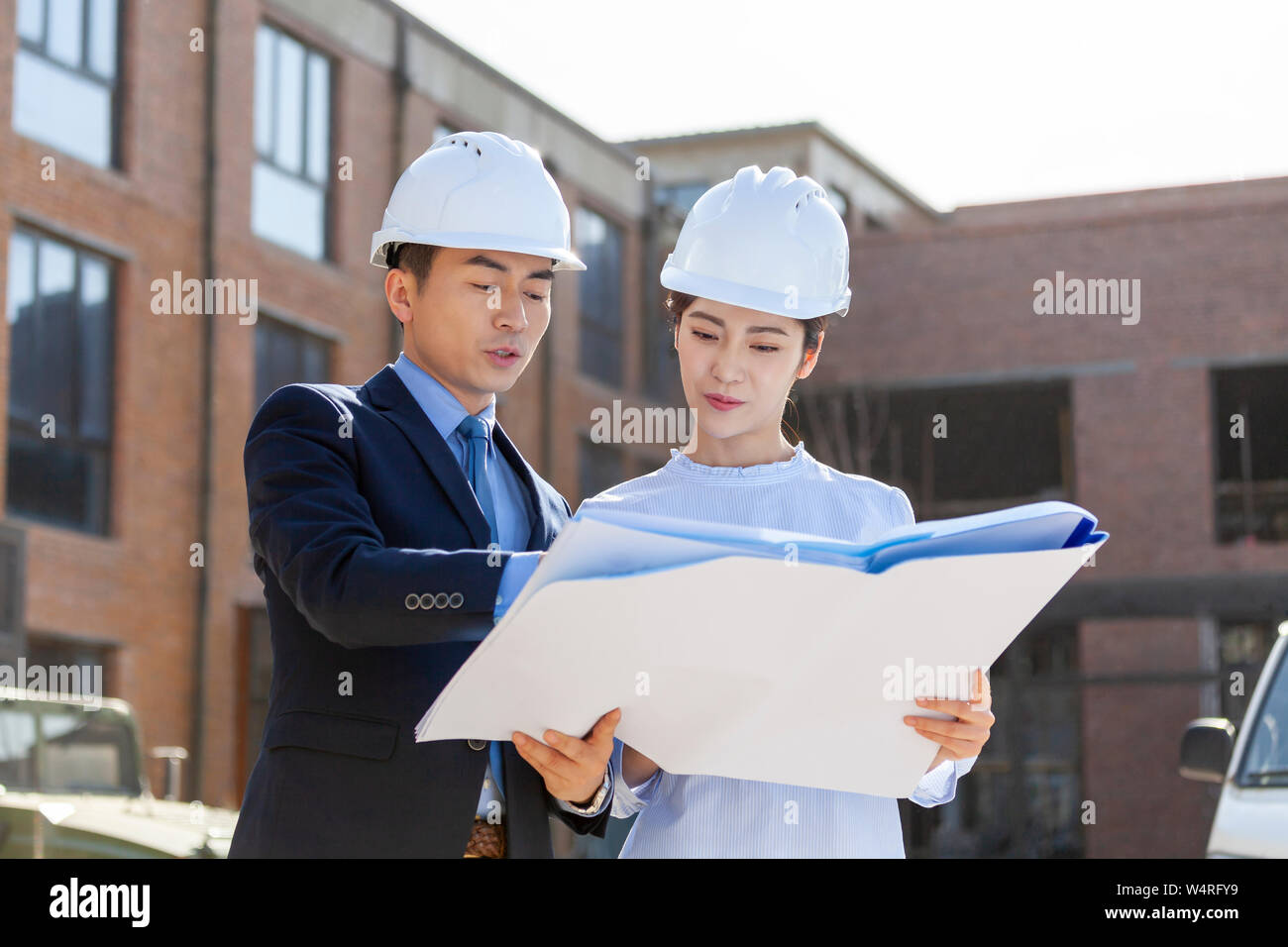 Two architects talking over blueprints, Beijing, China Stock Photo