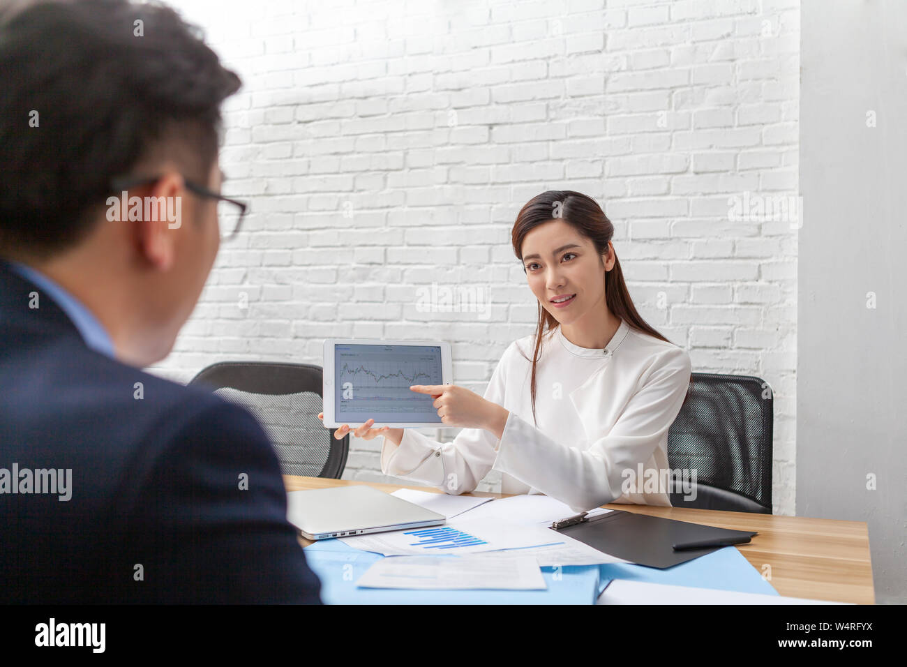 Woman behind desk holding tablet, Beijing, China Stock Photo