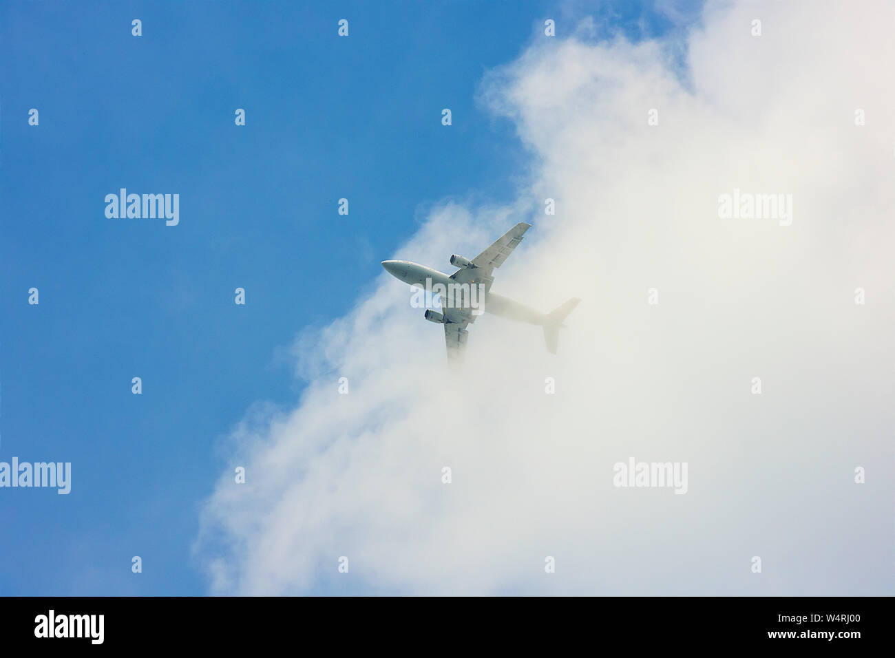 White jet emerging from clouds in sky, UK Stock Photo